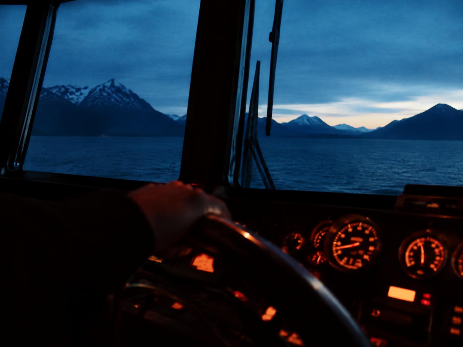 En hånd på roret på et skib i skumringen